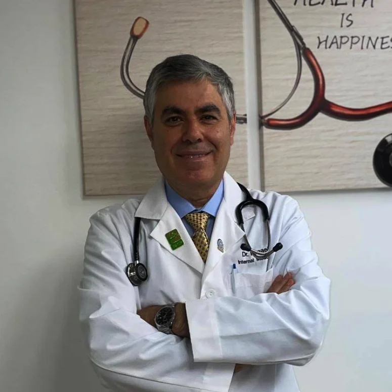 Dr. Ousama Ismael, a smiling internal medicine physician in a white coat